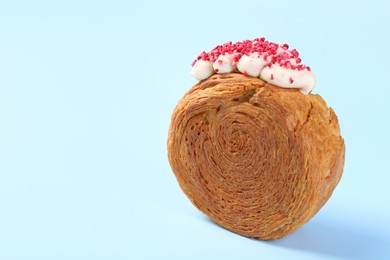 One supreme croissant with cream on light blue background, closeup with space for text. Tasty puff pastry