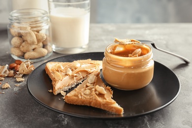 Jar with creamy peanut butter and toasts on plate