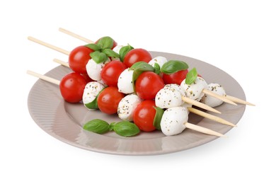 Photo of Plate of Caprese skewers with tomatoes, mozzarella balls, basil and spices isolated on white