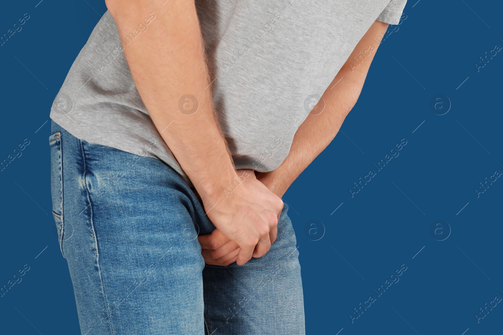 Photo of Man suffering from pain on blue background, closeup. Urology problems