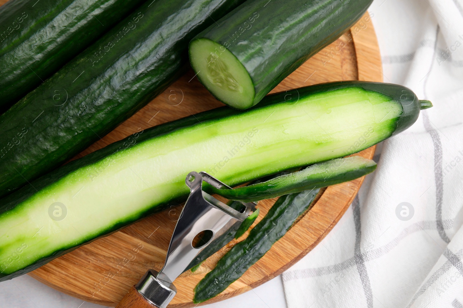 Photo of Fresh cucumbers and peeler on table, above view