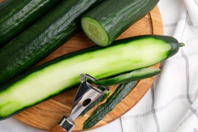 Fresh cucumbers and peeler on table, above view