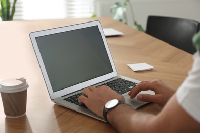 Photo of Freelancer working on laptop at table indoors, closeup