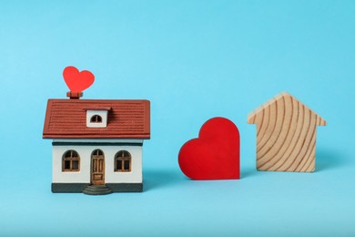 Photo of Long-distance relationship concept. Decorative heart between two house models on light blue background