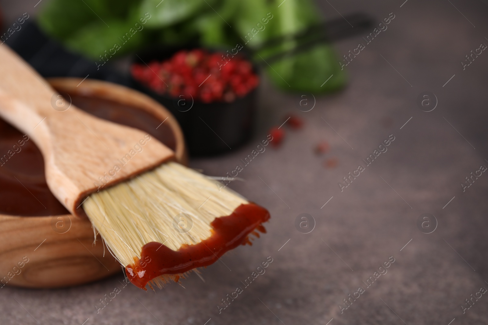Photo of Marinade in bowl and basting brush on brown table, selective focus. Space for text
