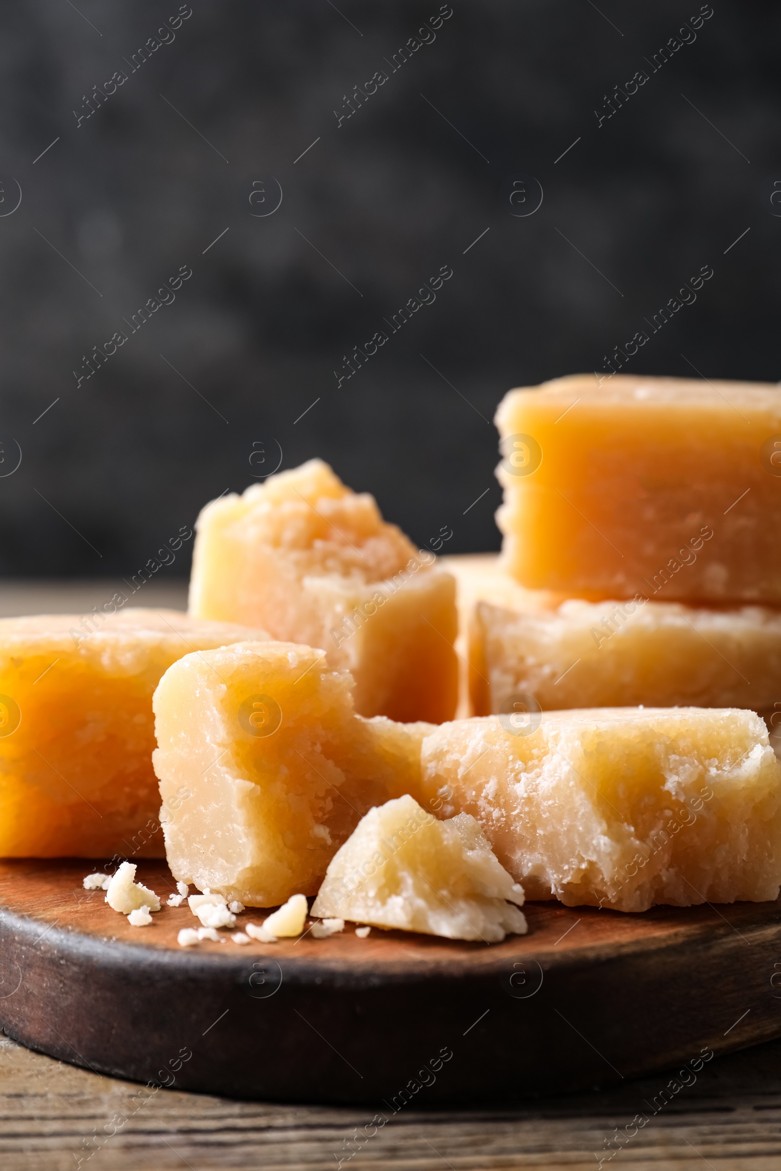 Photo of Parmesan cheese with wooden board on table, closeup