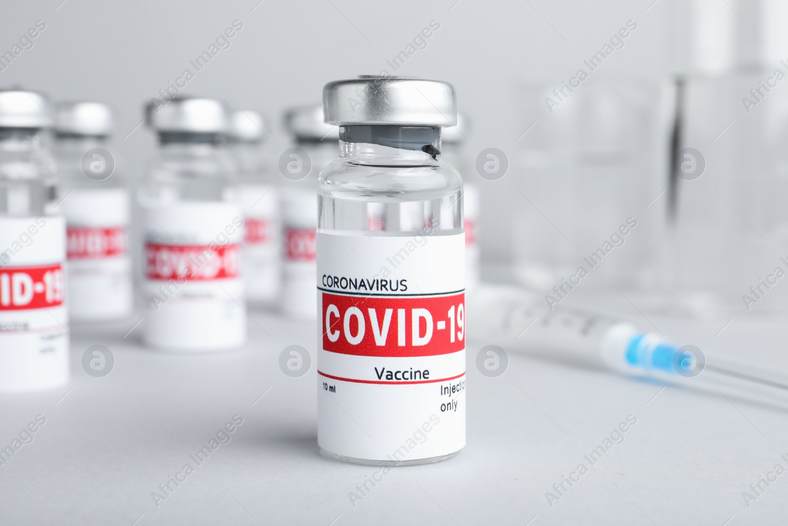 Photo of Glass vial with COVID-19 vaccine on light grey table