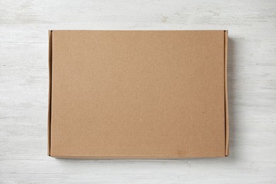 Cardboard box on white wooden background, top view. Space for design