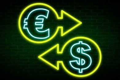 Money exchange neon sign. Yellow arrows, light blue euro and dollar symbols on brick wall