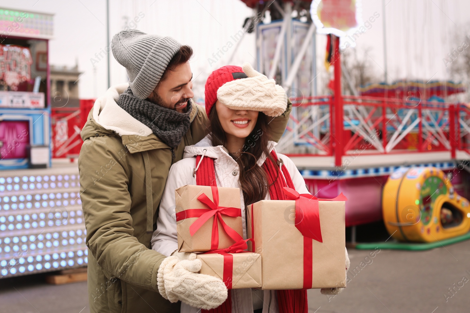 Photo of Lovely couple with Christmas presents in amusement park