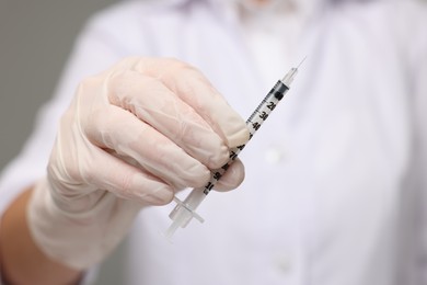 Doctor holding syringe with needle, closeup view