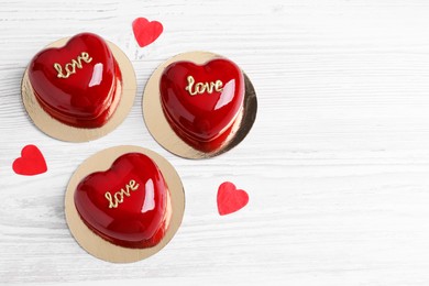 St. Valentine's Day. Delicious heart shaped cakes and confetti on white wooden table, flat lay. Space for text