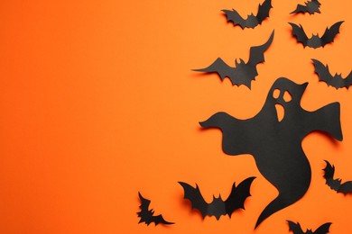 Photo of Flat lay composition with paper ghost and bats on orange background, space for text. Halloween celebration