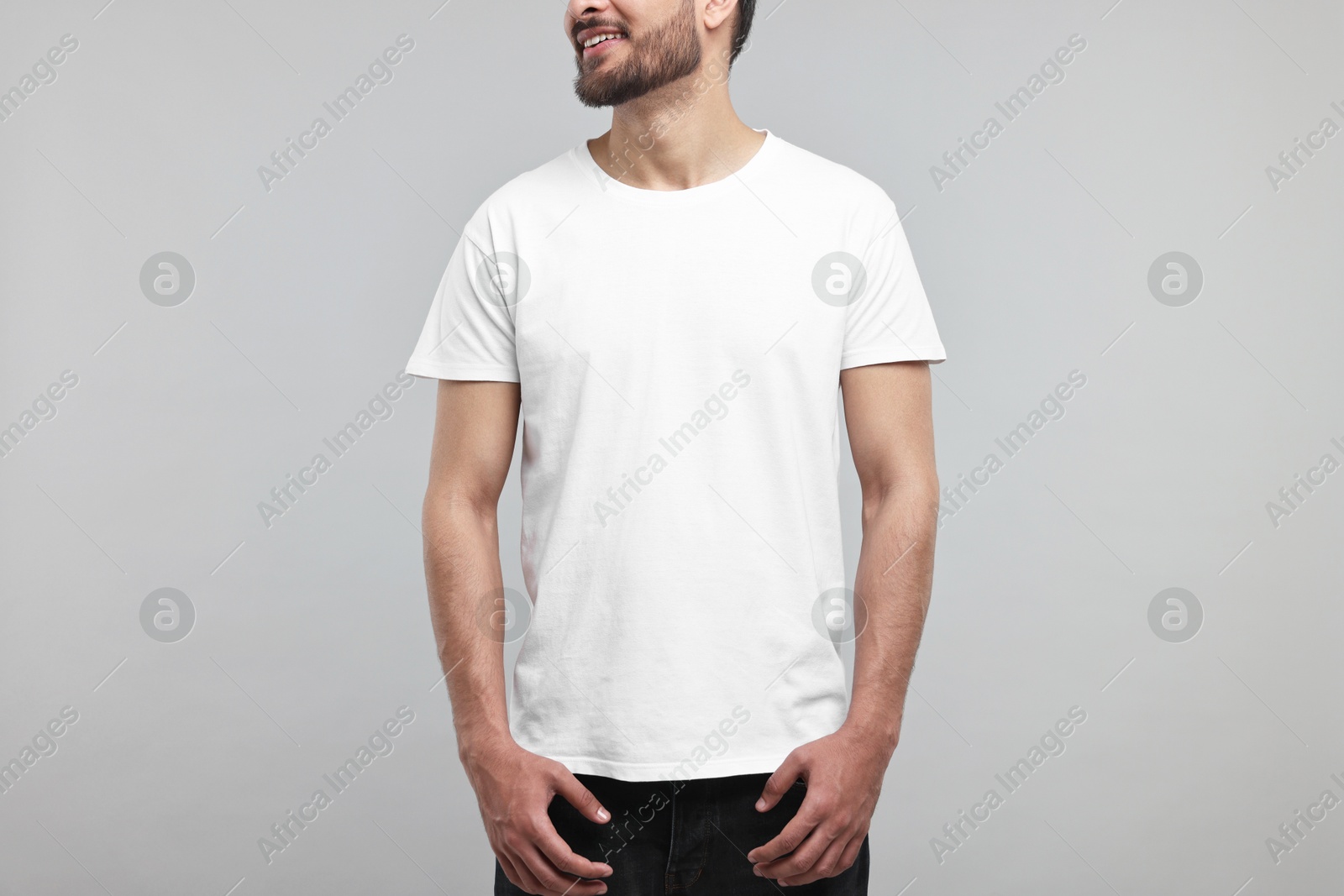 Photo of Smiling man in white t-shirt on grey background, closeup