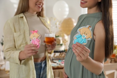 Photo of Happy pregnant woman and her friend with tasty cookies at baby shower party, closeup