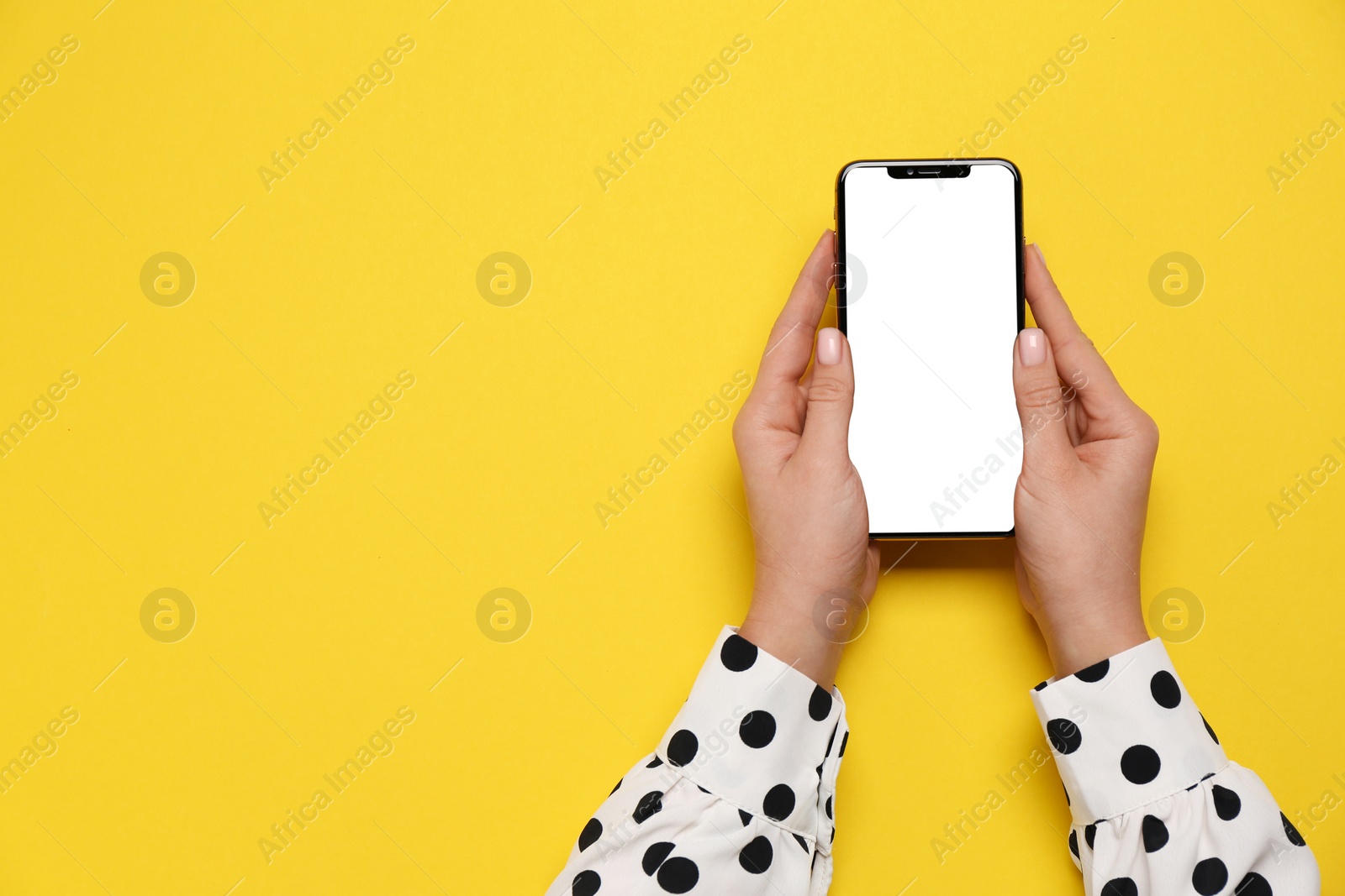 Photo of Woman with smartphone on yellow background, top view. Space for text