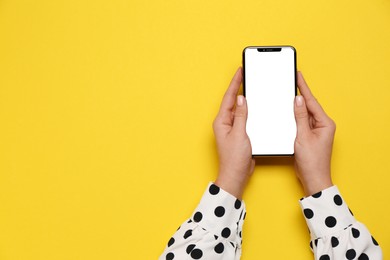 Photo of Woman with smartphone on yellow background, top view. Space for text