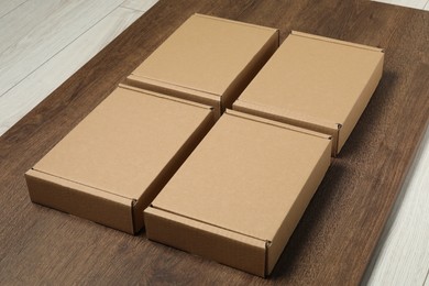 Photo of Closed cardboard boxes on wooden floor indoors. Packaging goods