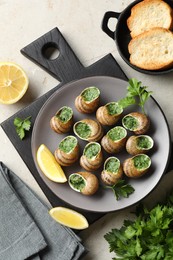 Photo of Delicious cooked snails served on light table, flat lay