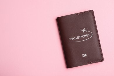 Passport in brown leather case on pink background, top view. Space for text