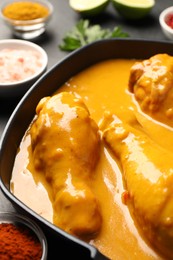 Photo of Tasty chicken curry and ingredients on black table, closeup