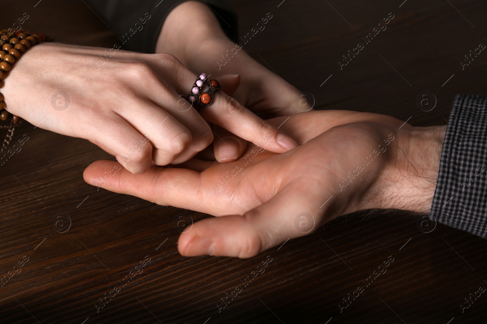 Photo of Chiromancer reading lines on man's palm at table, closeup