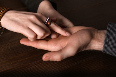 Chiromancer reading lines on man's palm at table, closeup