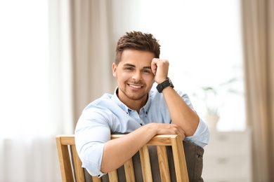 Photo of Portrait of handsome young man sitting on chair in room