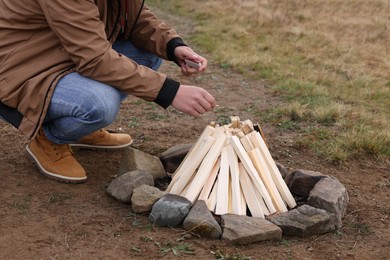 Photo of Man making bonfire outdoors, closeup. Camping season