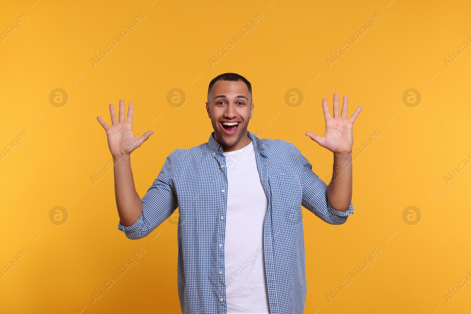 Photo of Man giving high five with both hands on yellow background