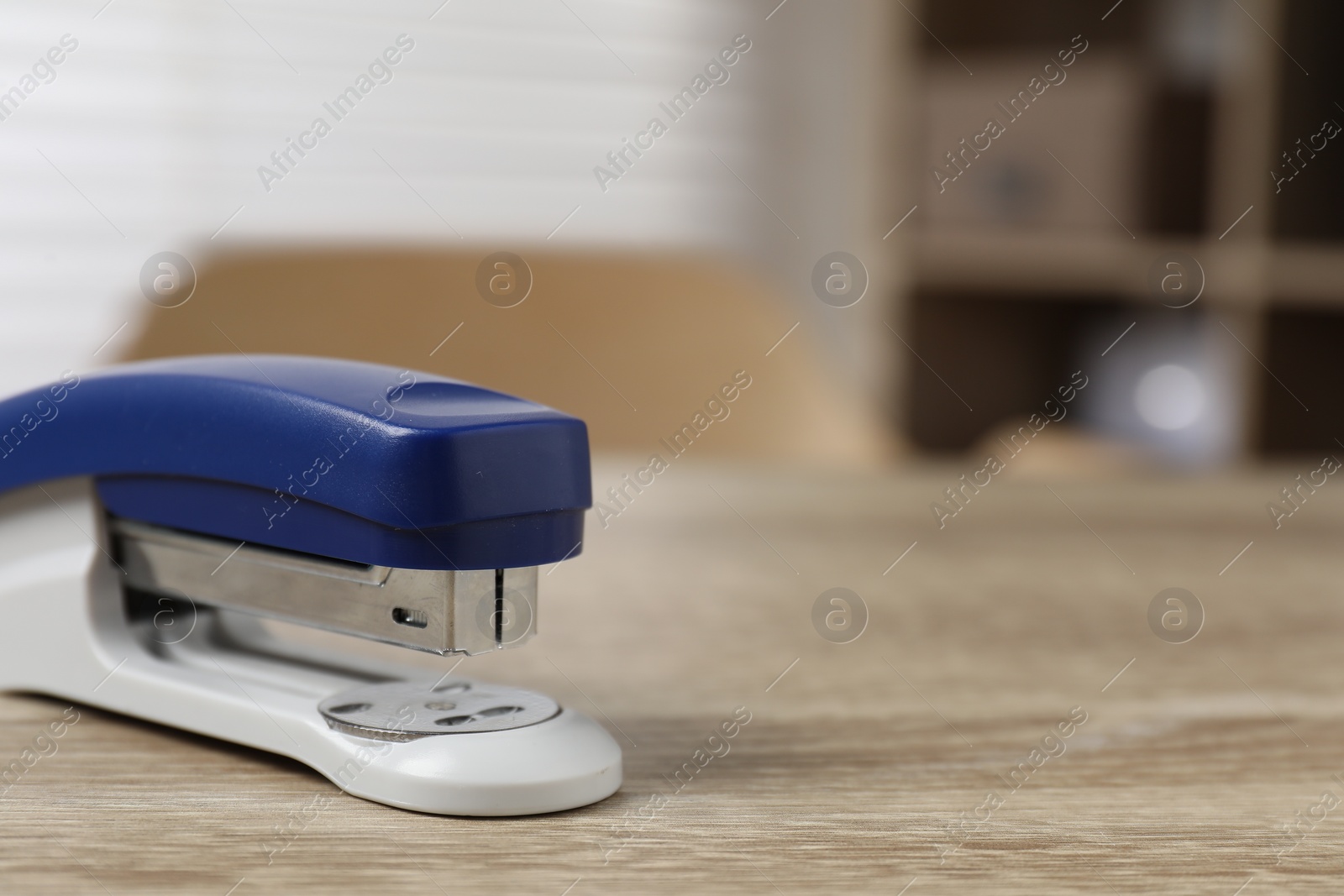 Photo of Bright stapler on wooden table indoors, closeup. Space for text