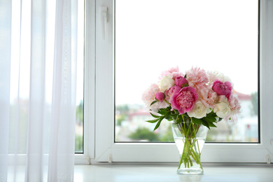 Beautiful peony bouquet in vase on windowsill indoors. Space for text