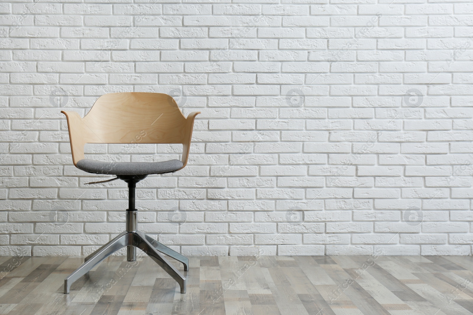 Photo of Comfortable office chair near white brick wall indoors. Space for text