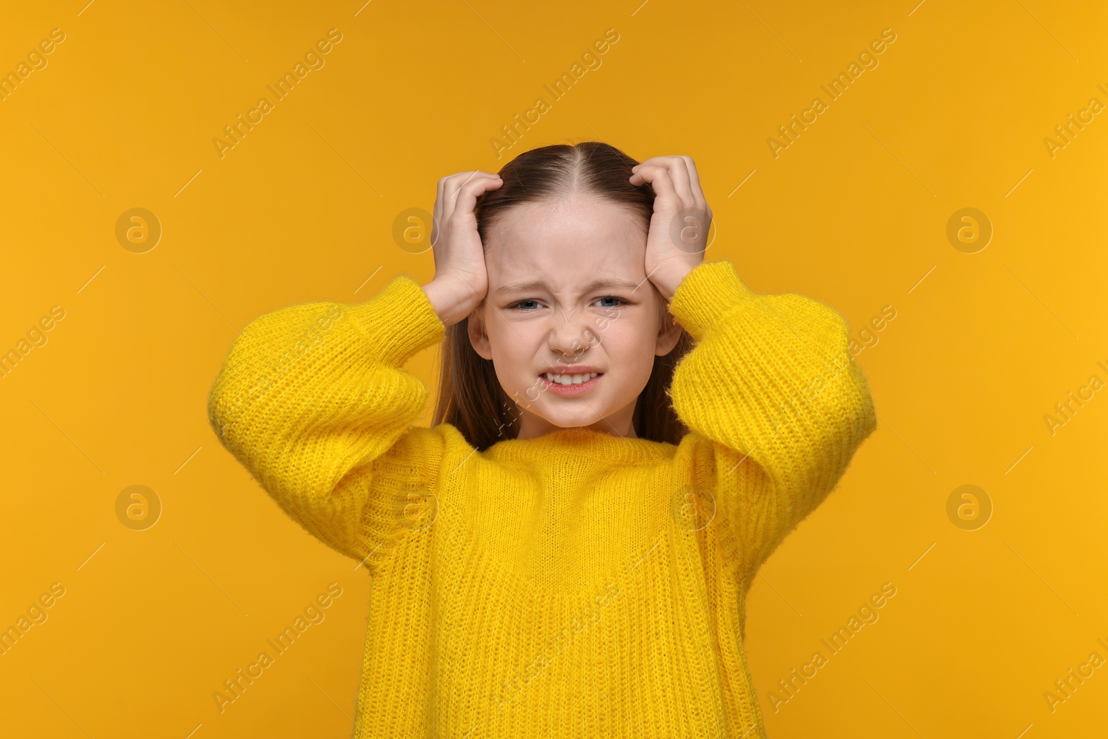 Photo of Little girl suffering from headache on yellow background