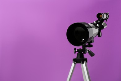 Photo of Tripod with modern telescope on purple background, closeup. Space for text