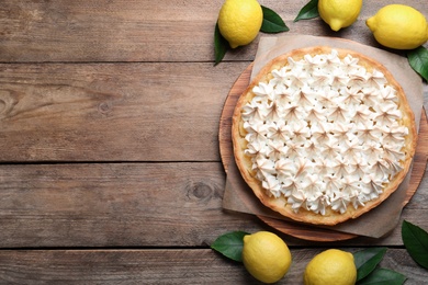 Photo of Flat lay composition with delicious lemon meringue pie on wooden table. Space for text