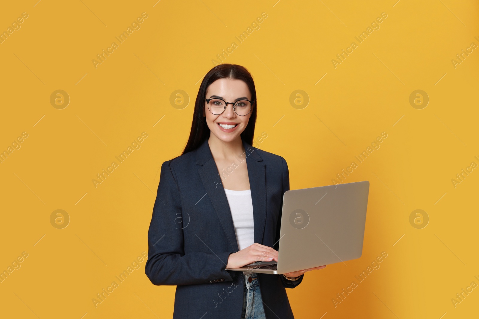 Photo of Young woman with modern laptop on yellow background