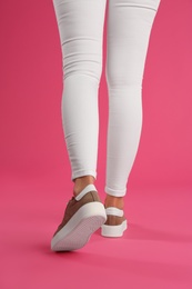 Photo of Woman wearing shoes on pink background, closeup