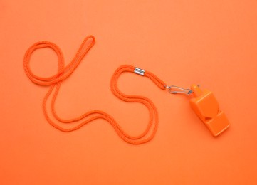 Photo of One color whistle with cord on orange background, top view