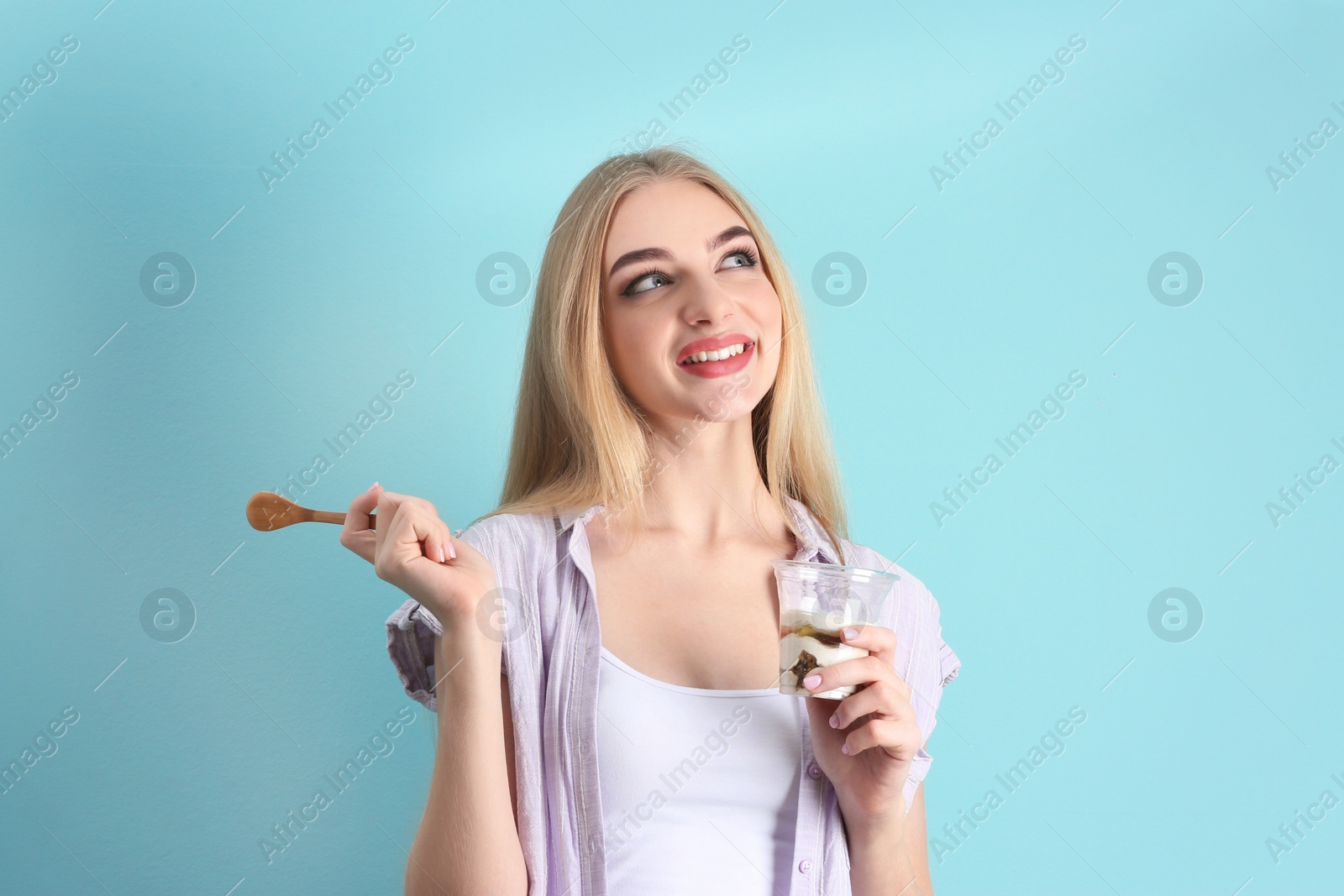 Photo of Young woman with yogurt on color background