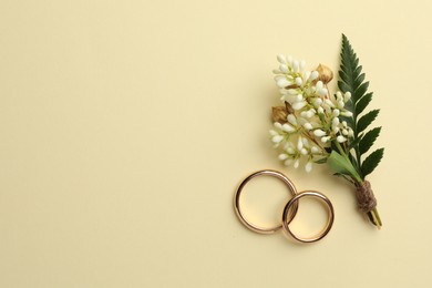 Photo of Small stylish boutonnieres and rings on beige background, flat lay. Space for text