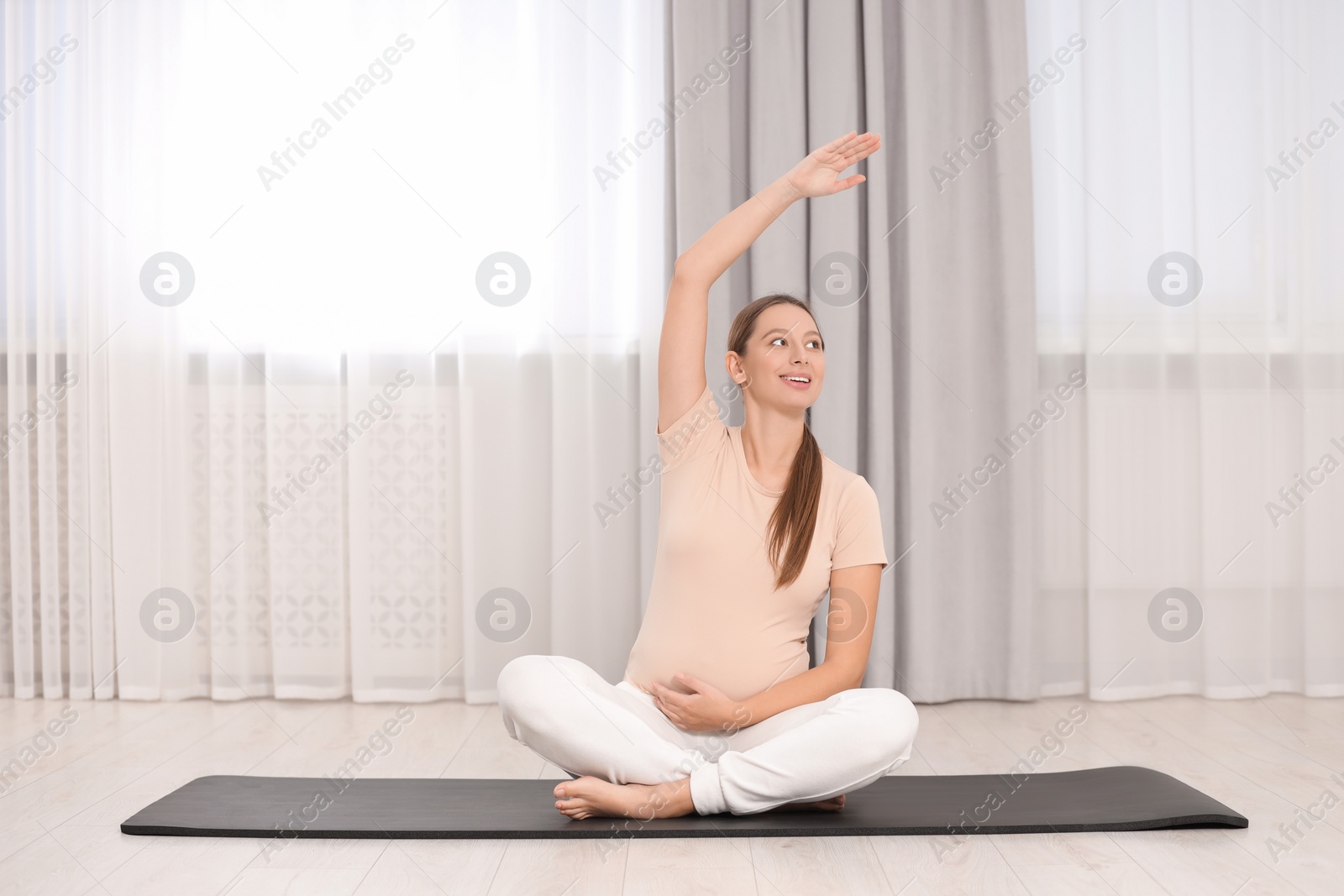 Photo of Pregnant woman doing exercises on yoga mat at home