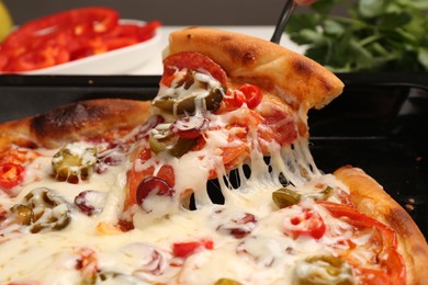 Photo of Taking piece of delicious pizza Diablo from baking tray, closeup