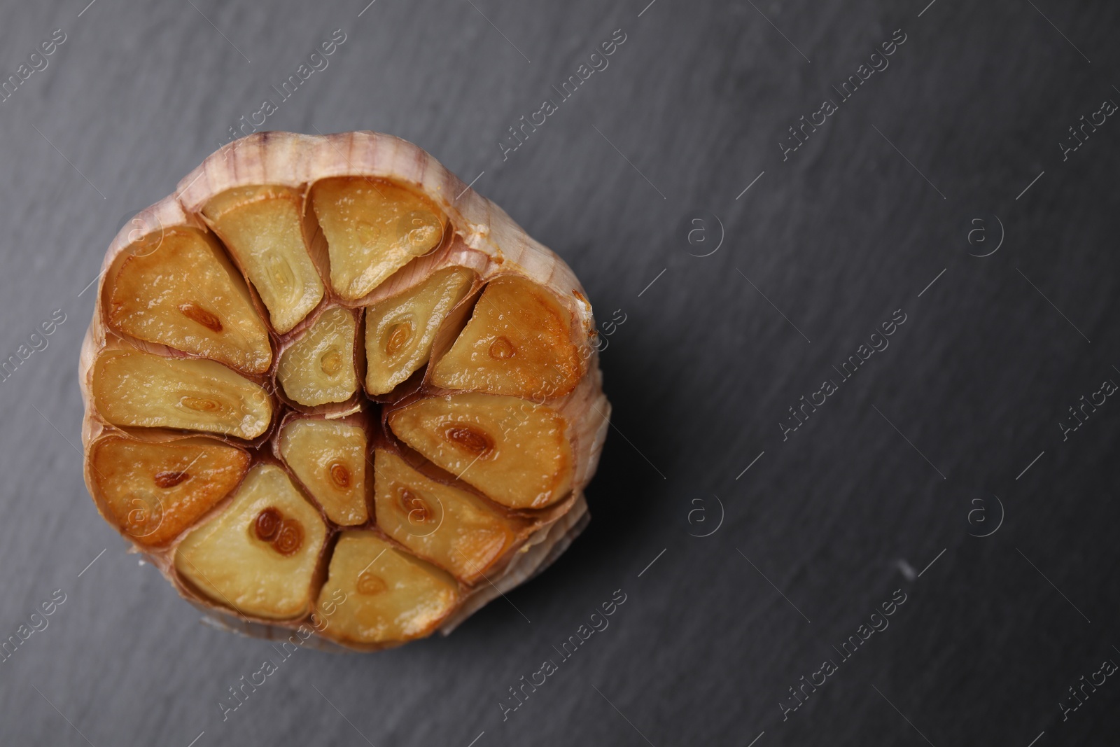 Photo of Head of fried garlic on dark gray table, closeup. Space for text