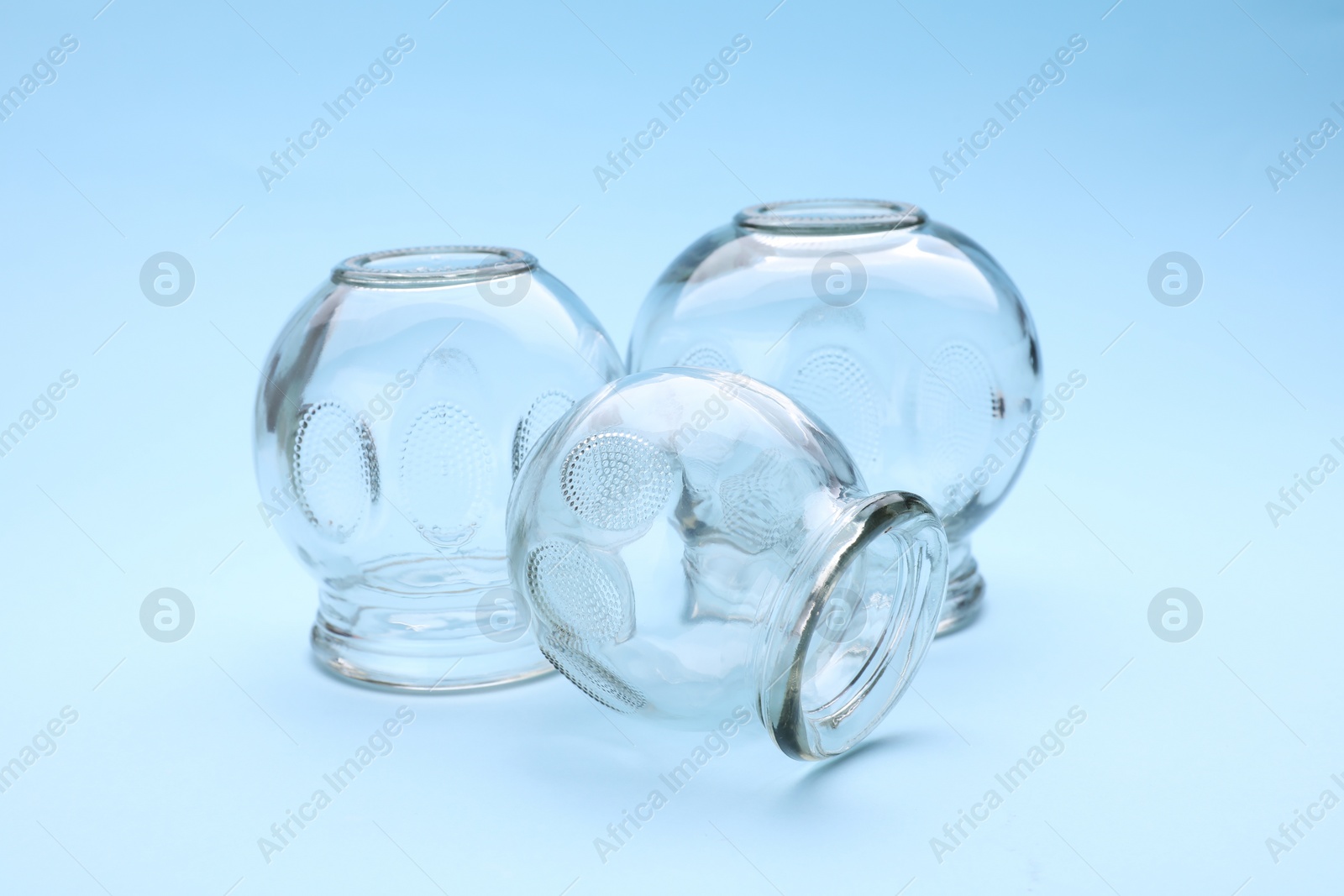 Photo of Glass cups on light blue background. Cupping therapy