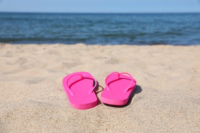 Photo of Stylish pink flip flops on beach sand, space for text