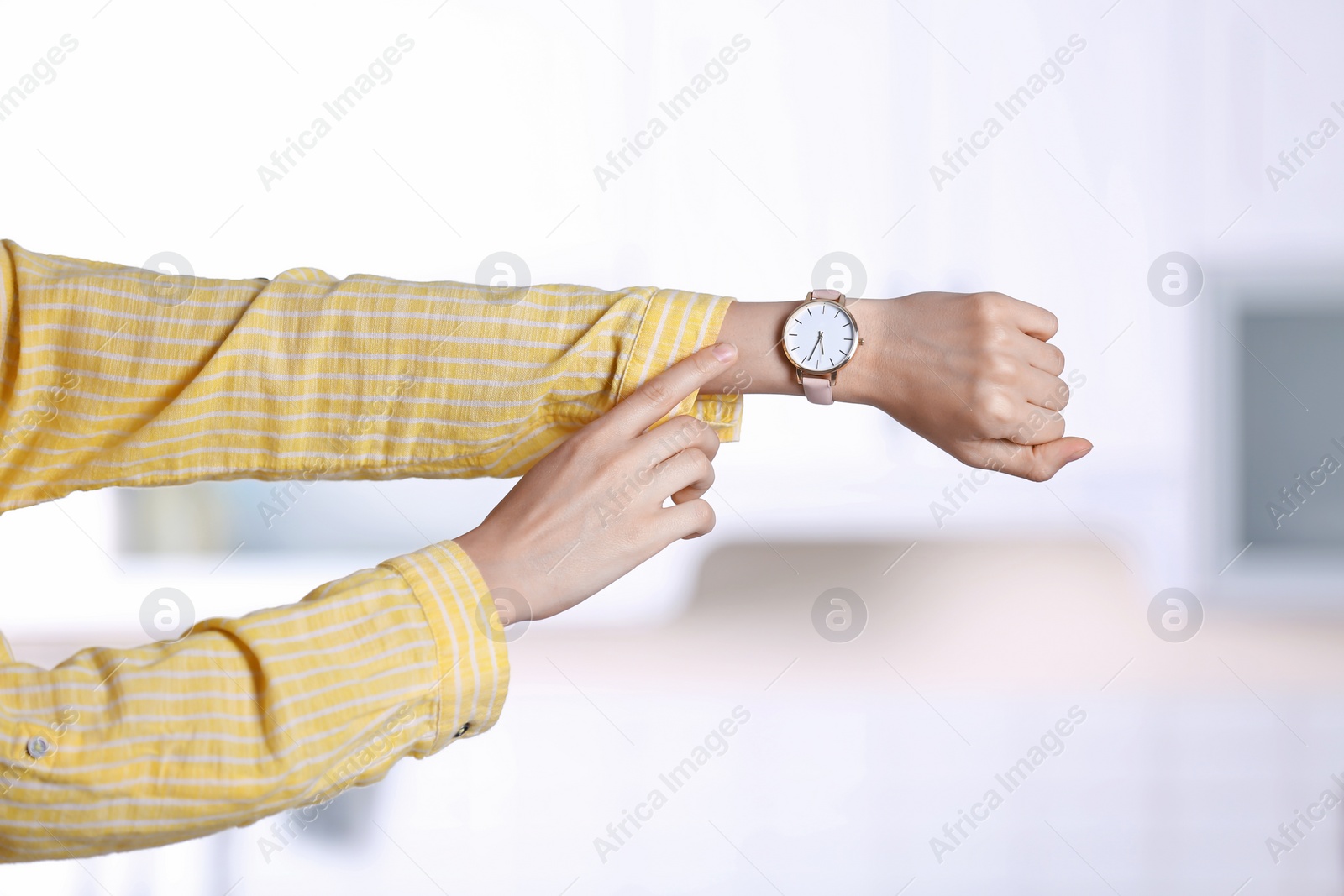 Photo of Young woman with wristwatch on blurred background. Time concept