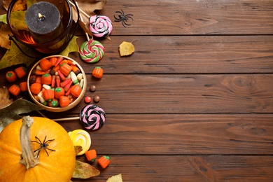 Flat lay composition with pumpkin head Jack lantern and Halloween treats on wooden background. Space for text