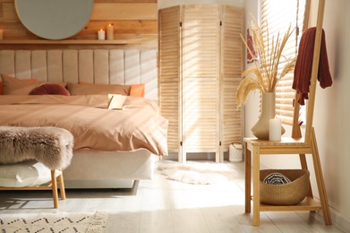 Photo of Bed with brown linens in cozy bedroom. Interior design