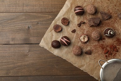 Photo of Different delicious chocolate truffles on wooden table, top view. Space for text